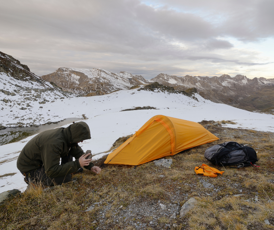 un homme qui installe sa tente dans la montagne