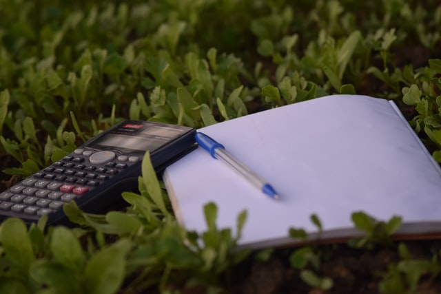 Calculatrice et carnet dans une pelouse.