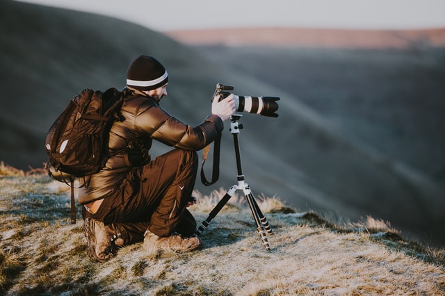 Photographe digital nomad qui prend en photo un paysage montagneux 