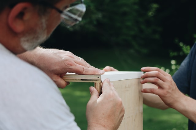 Homme et femme qui assemblent des planches de bois pour aménager un fourgon.