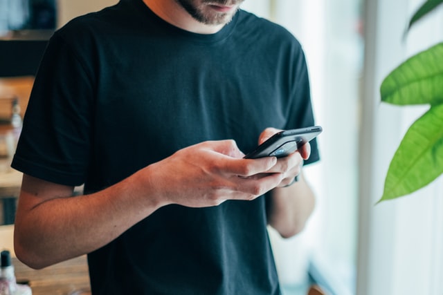 Homme devant son smartphone cherchant à réduire sa consommation d'écran
