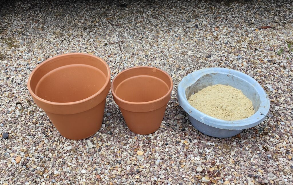 1 grand pot en terre cuite, un plus petit pot en terre cuite et du sable pour fabriquer un frigo du désert