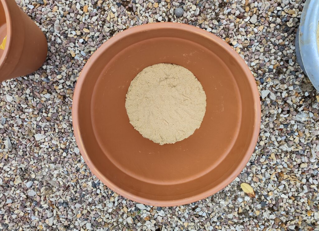 grand pot en terre cuite avec du sable humide au fond