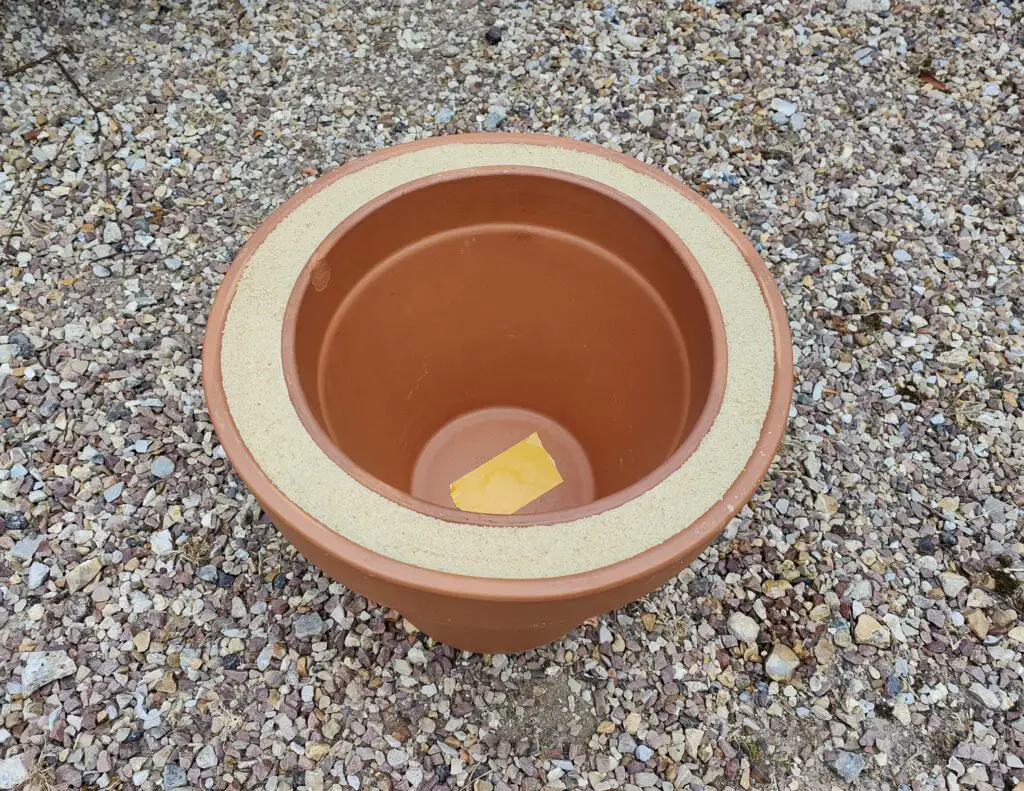 petit pot dans le grand pot en terre cuite avec le sable entre les deuxx
