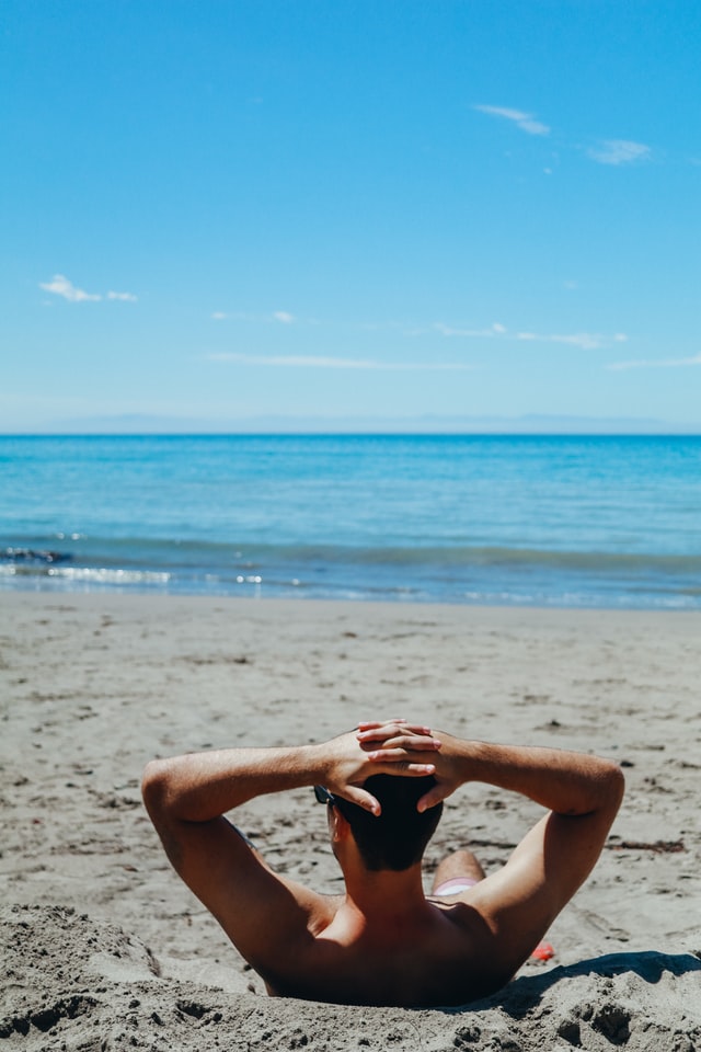 homme qui bronze au soleil sur une plage lors de ses vacances différentes d'un voyage en van